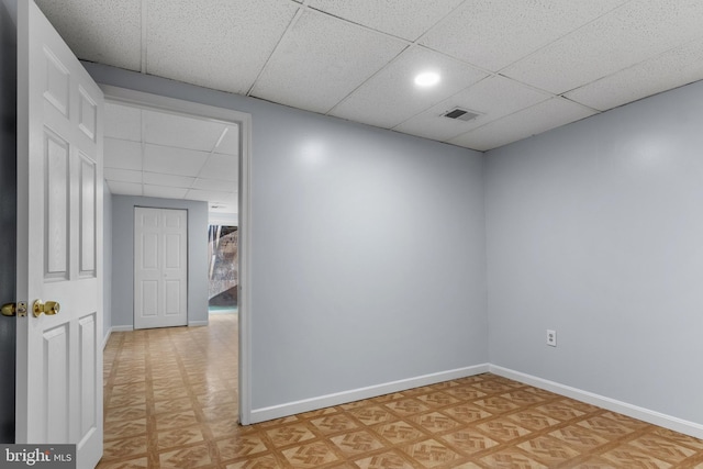 unfurnished room with visible vents, a drop ceiling, baseboards, and light floors