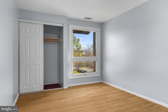 unfurnished bedroom with baseboards, a closet, visible vents, and light wood-type flooring