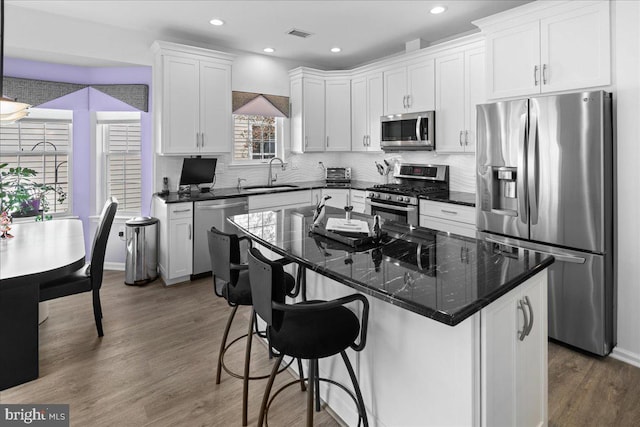 kitchen featuring a sink, stainless steel appliances, tasteful backsplash, white cabinetry, and dark wood finished floors