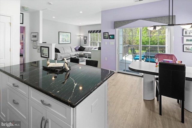 kitchen featuring dark stone countertops, recessed lighting, light wood-style floors, white cabinets, and a center island