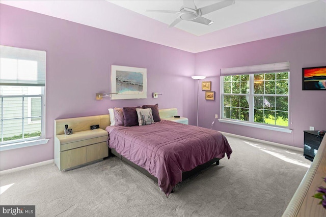 bedroom with light colored carpet, baseboards, a ceiling fan, and multiple windows