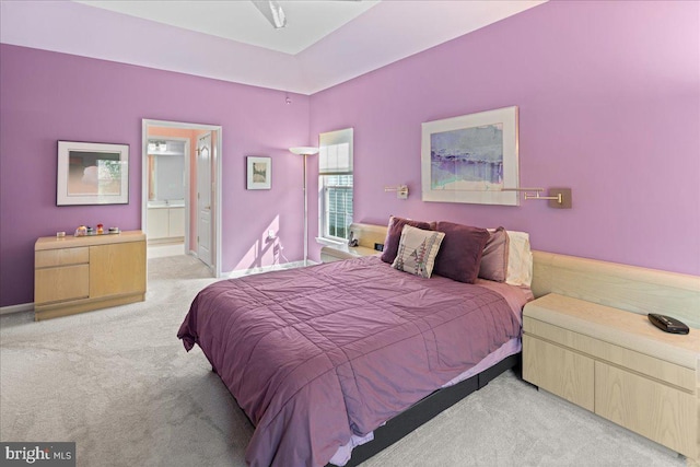 bedroom with ensuite bath, carpet flooring, and baseboards