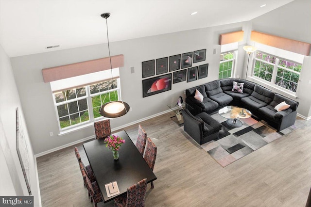 living area featuring visible vents, baseboards, wood finished floors, and plenty of natural light