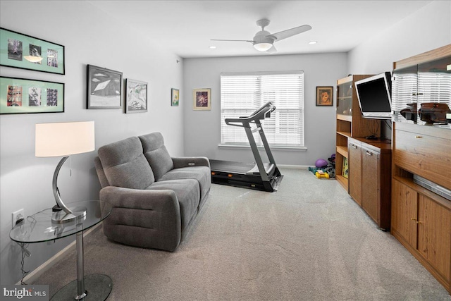 workout room with baseboards, light carpet, and ceiling fan