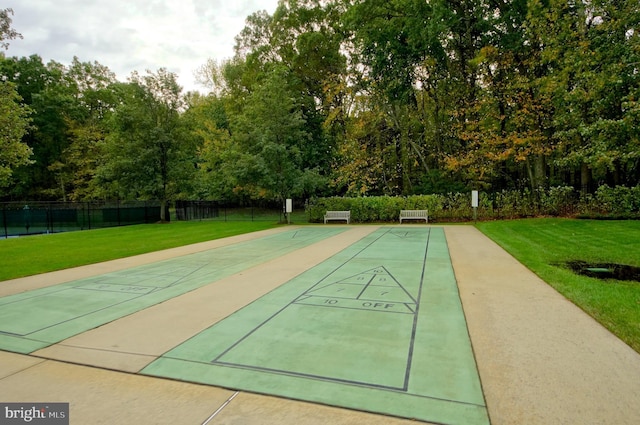 view of community with fence, a yard, and shuffleboard
