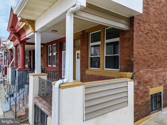 entrance to property with brick siding and a porch