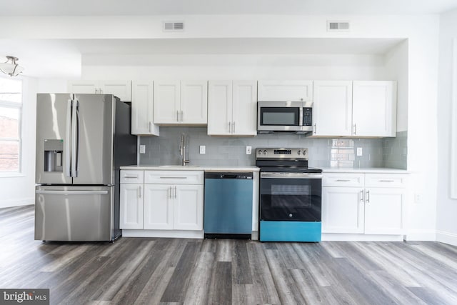 kitchen with a sink, light countertops, appliances with stainless steel finishes, dark wood-type flooring, and visible vents