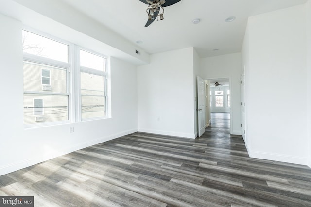 interior space featuring baseboards, visible vents, a ceiling fan, and dark wood-style floors