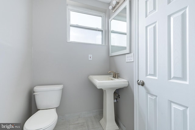bathroom featuring baseboards, tile patterned flooring, and toilet