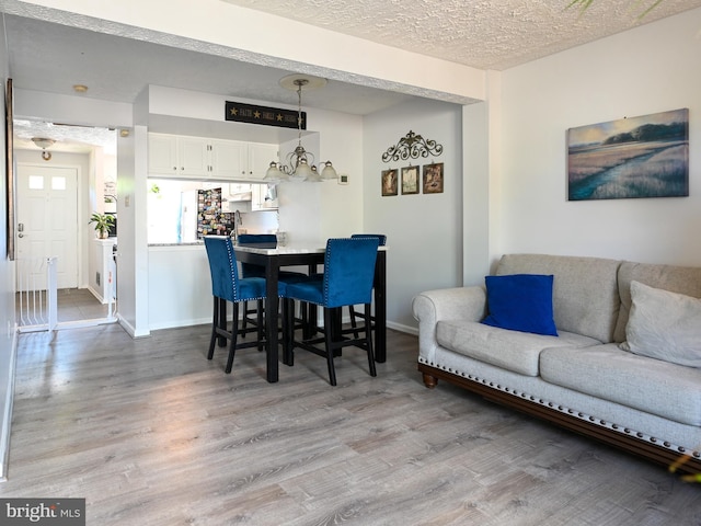 8554 Koluder Ct, Lorton, VA 22079 - dining area with light wood-style floors, baseboards, a textured ceiling, and a chandelier