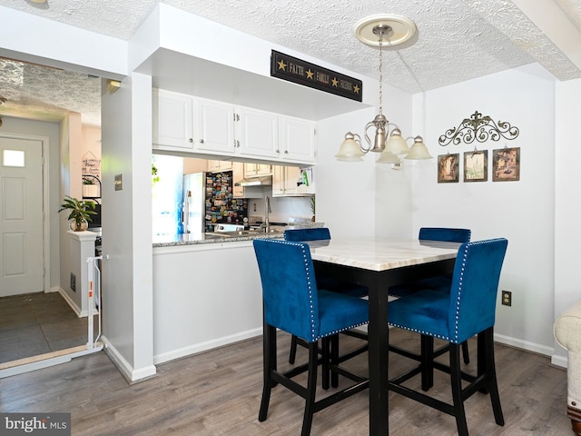 8554 Koluder Ct, Lorton, VA 22079 - dining room with dark wood-type flooring, a textured ceiling, a chandelier, and baseboards