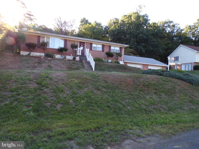 single story home featuring brick siding, a front yard, and a detached garage