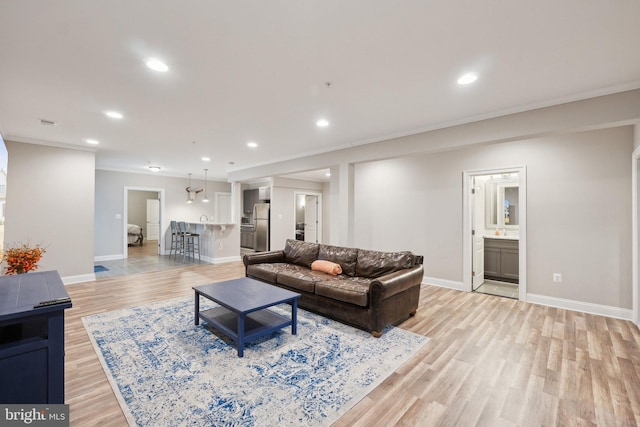 living area with baseboards, recessed lighting, light wood-style floors, and crown molding