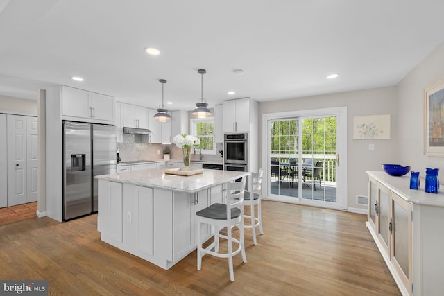 1004 Union Church Rd, Mclean, VA 22102 - kitchen featuring under cabinet range hood, appliances with stainless steel finishes, a kitchen island, white cabinetry, and light wood-type flooring