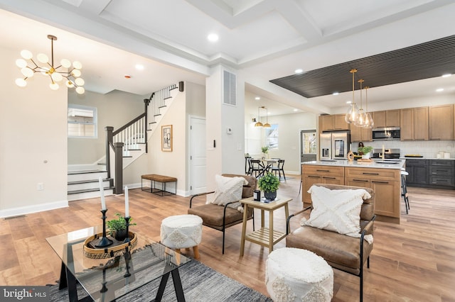 living area with a chandelier, light wood-type flooring, visible vents, and stairs