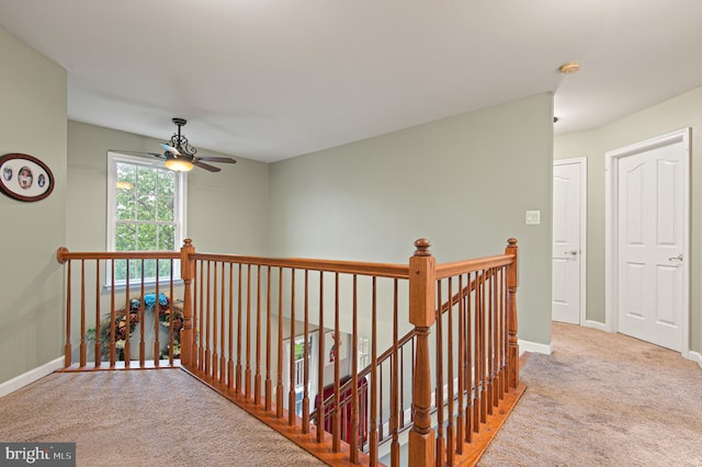corridor with an upstairs landing, carpet, and baseboards