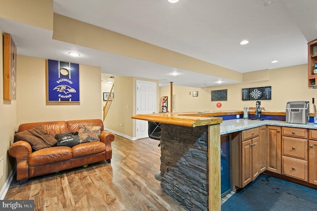 kitchen featuring light stone counters, wood finished floors, baseboards, recessed lighting, and brown cabinets