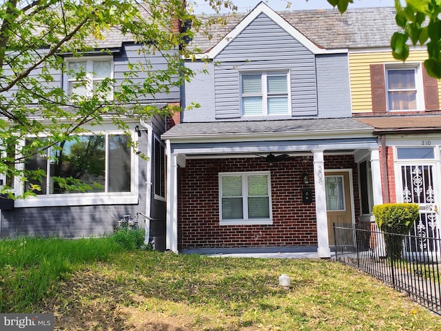 view of front of home with fence, covered porch, and brick siding