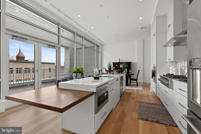 101 N Queen St Unit 402, Lancaster, PA 17603 - kitchen featuring modern cabinets, wall chimney exhaust hood, appliances with stainless steel finishes, and light wood finished floors
