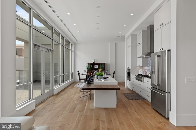 101 N Queen St Unit 402, Lancaster, PA 17603 - kitchen with wall chimney exhaust hood, stainless steel appliances, a center island, light wood-style floors, and white cabinetry