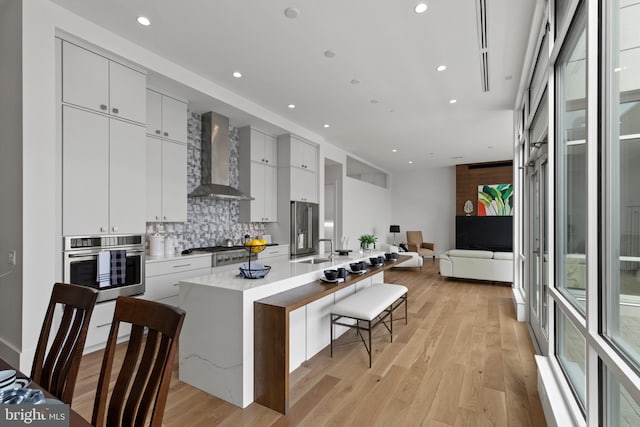 101 N Queen St Unit 402, Lancaster, PA 17603 - kitchen with recessed lighting, stainless steel appliances, backsplash, wall chimney range hood, and modern cabinets
