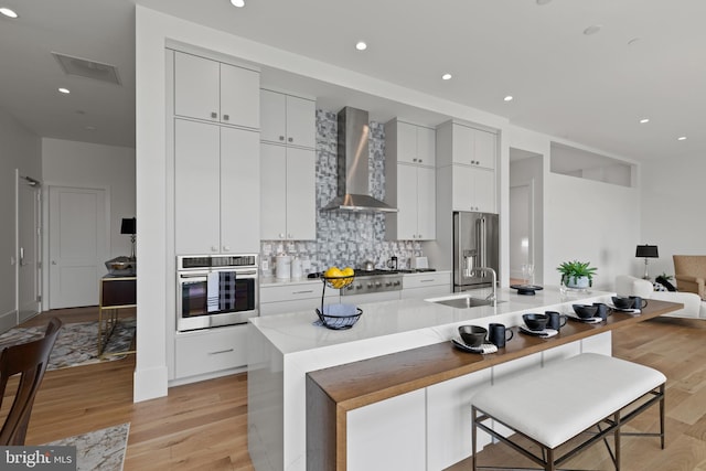 101 N Queen St Unit 402, Lancaster, PA 17603 - kitchen featuring wall chimney range hood, a sink, stainless steel appliances, light wood finished floors, and backsplash