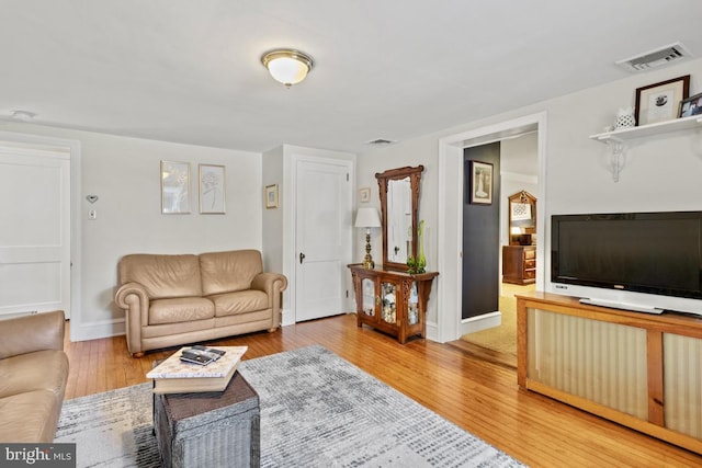 living room with visible vents, wood finished floors, and baseboards