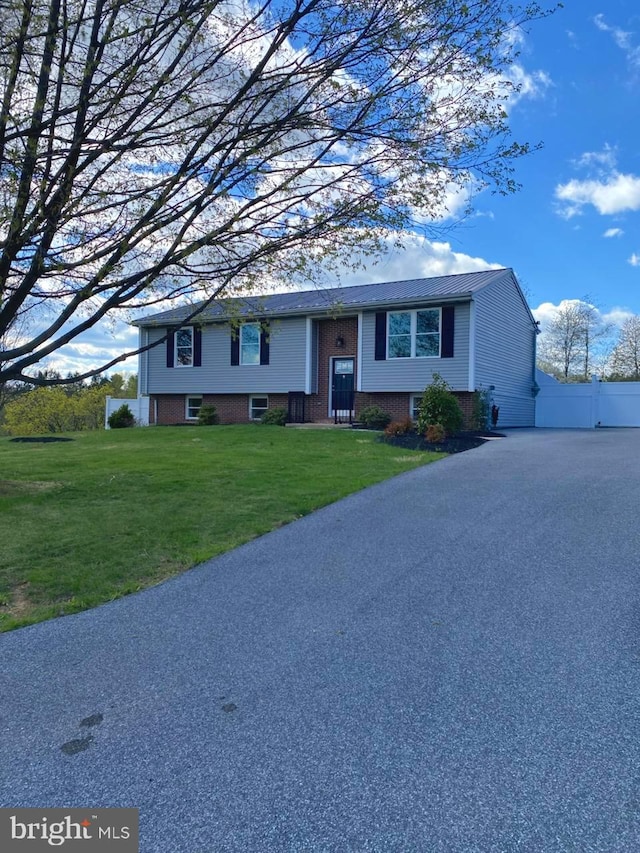 raised ranch with a front lawn and brick siding