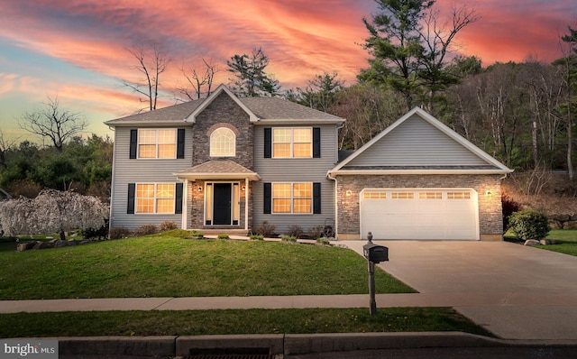 colonial house with a lawn, driveway, and a garage