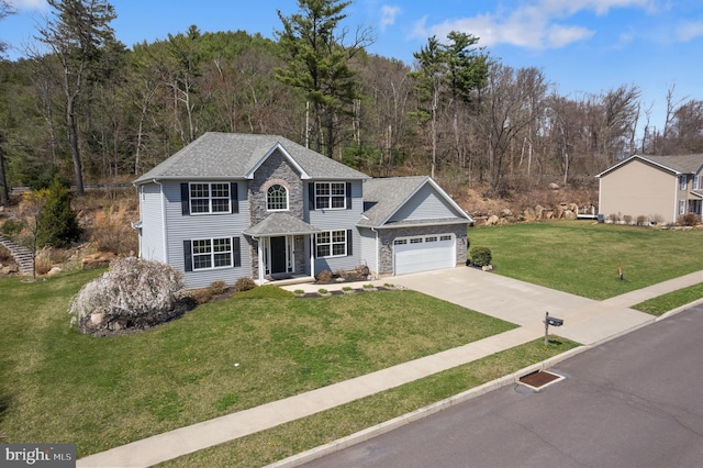 view of front of home featuring driveway, stone siding, a shingled roof, an attached garage, and a front yard