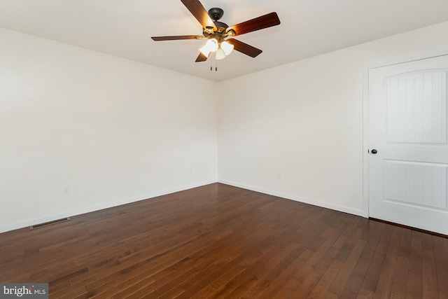 empty room featuring dark wood-style flooring, a ceiling fan, visible vents, and baseboards