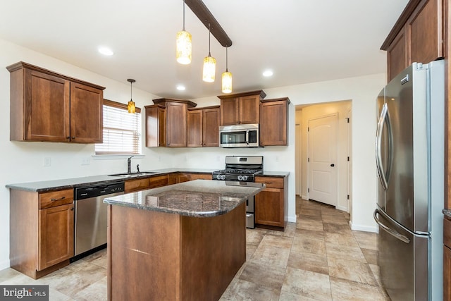 kitchen with a center island, dark stone countertops, hanging light fixtures, a sink, and stainless steel appliances