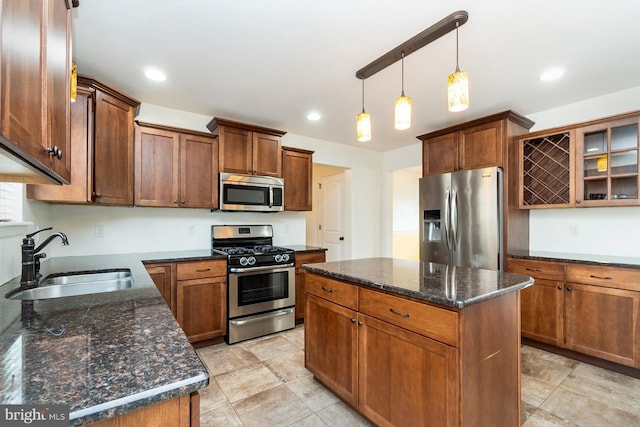kitchen with a center island, a sink, dark stone countertops, decorative light fixtures, and appliances with stainless steel finishes