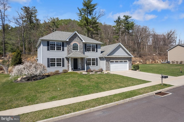 colonial-style house with driveway, stone siding, a shingled roof, an attached garage, and a front yard