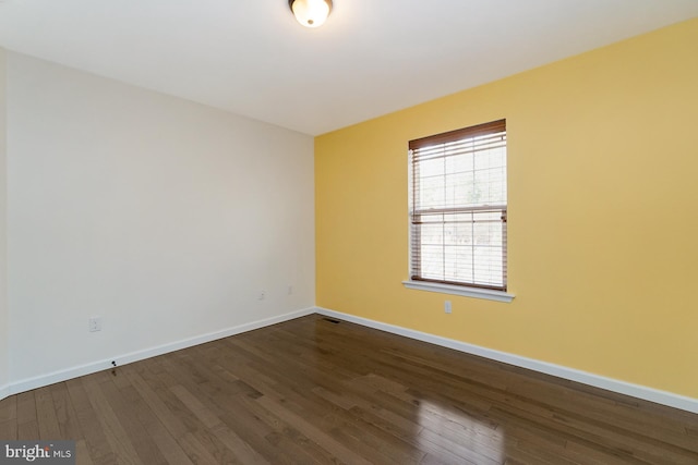 unfurnished room featuring baseboards, visible vents, and dark wood-style floors