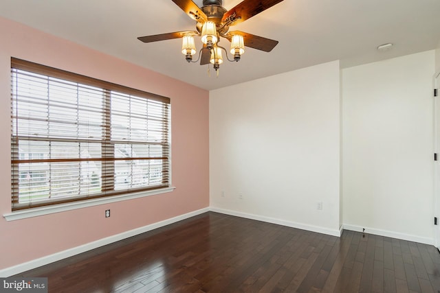 spare room with dark wood-style flooring, a ceiling fan, and baseboards