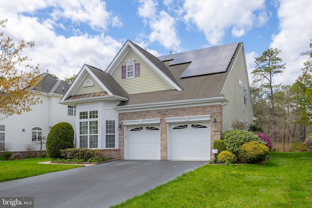 traditional-style house featuring a front yard, aphalt driveway, brick siding, and solar panels