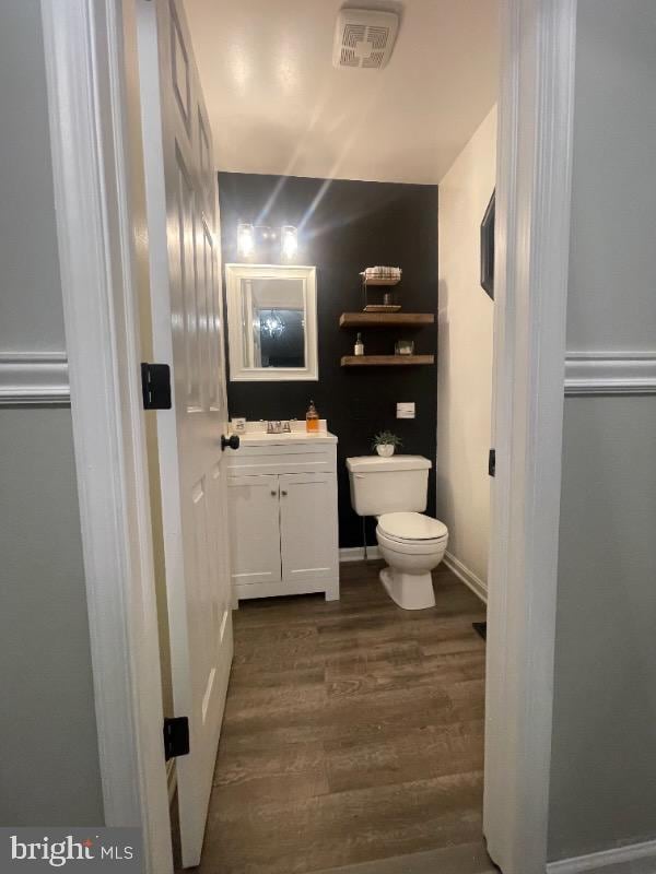 half bathroom featuring toilet, vanity, and wood finished floors