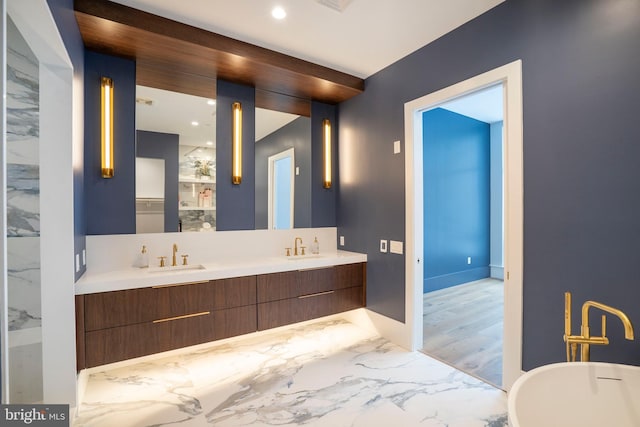 bathroom featuring a sink, double vanity, recessed lighting, a freestanding tub, and marble finish floor