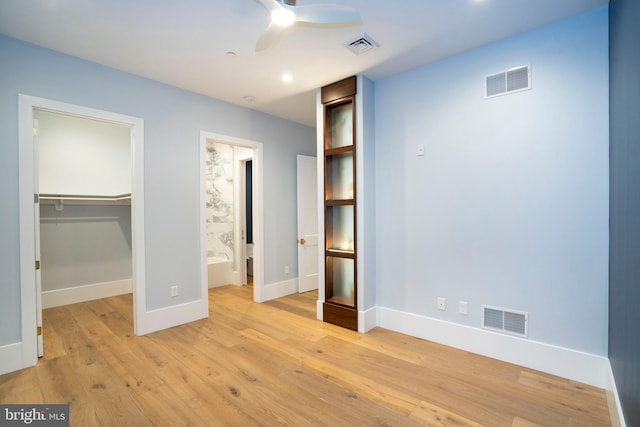 unfurnished bedroom featuring baseboards, visible vents, a spacious closet, and light wood finished floors