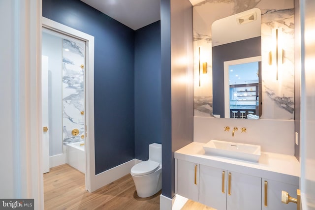 full bathroom with vanity, a bathtub, toilet, visible vents, and wood finished floors