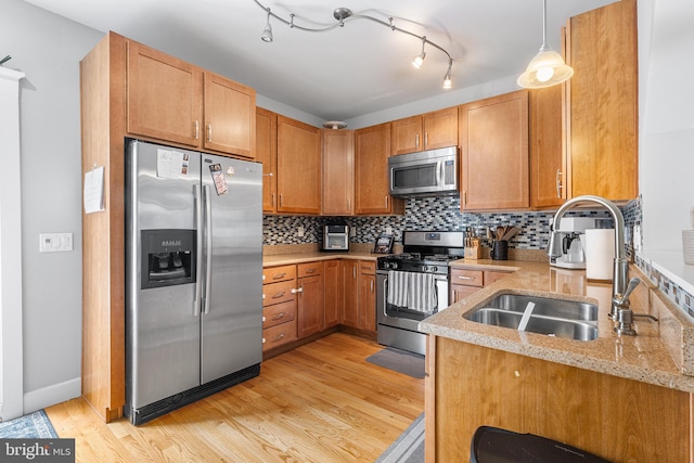kitchen featuring light wood-style flooring, a sink, appliances with stainless steel finishes, and tasteful backsplash