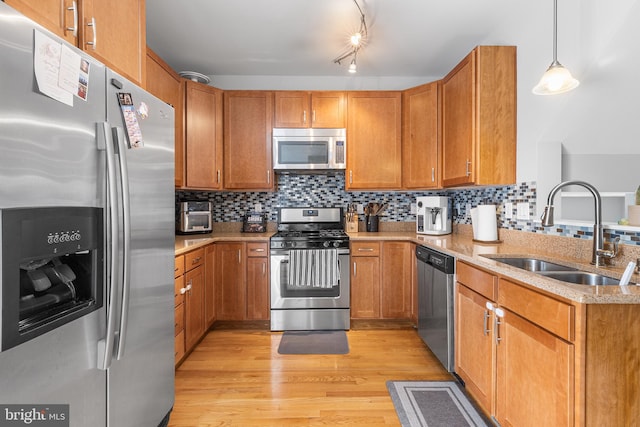 kitchen featuring brown cabinets, light wood-style flooring, appliances with stainless steel finishes, and a sink
