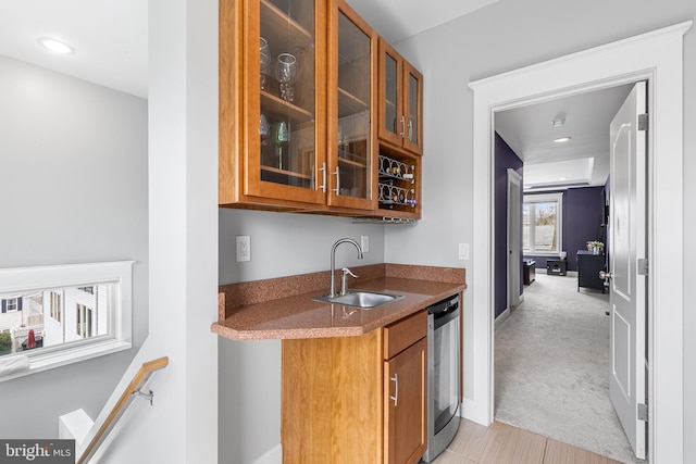 bar with stainless steel dishwasher, a sink, wet bar, baseboards, and light colored carpet