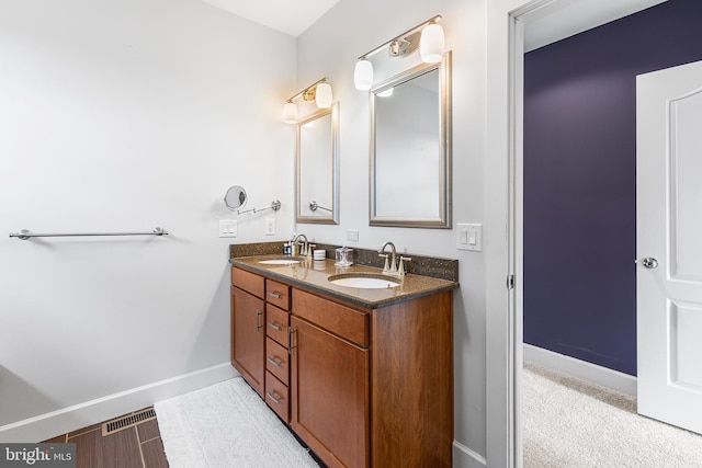 bathroom featuring baseboards, a sink, and double vanity