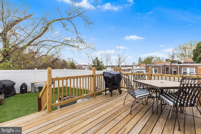 deck with a lawn, outdoor dining area, fence, and area for grilling