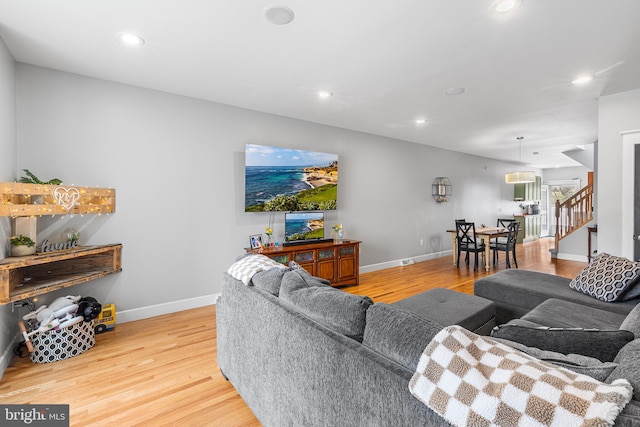 living area with baseboards, wood finished floors, stairs, and recessed lighting