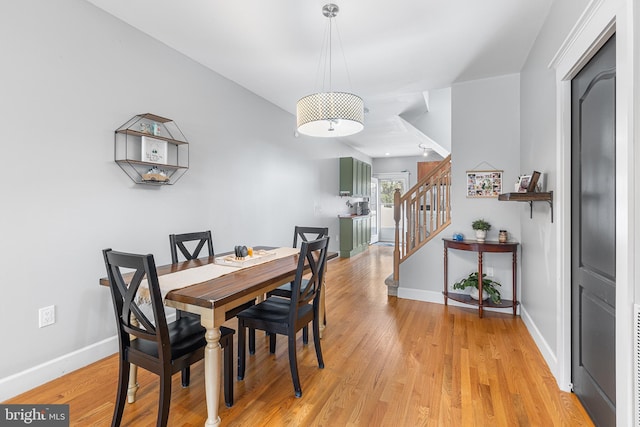 dining area featuring light wood-style floors, stairway, and baseboards