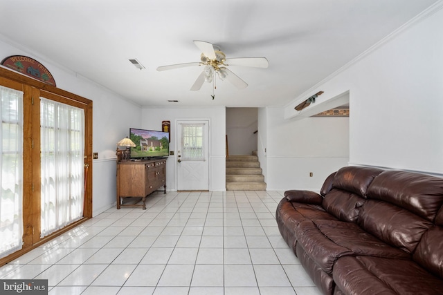 living room featuring visible vents, crown molding, stairs, ceiling fan, and light tile patterned floors