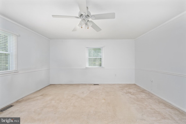 carpeted empty room featuring crown molding, ceiling fan, visible vents, and baseboards